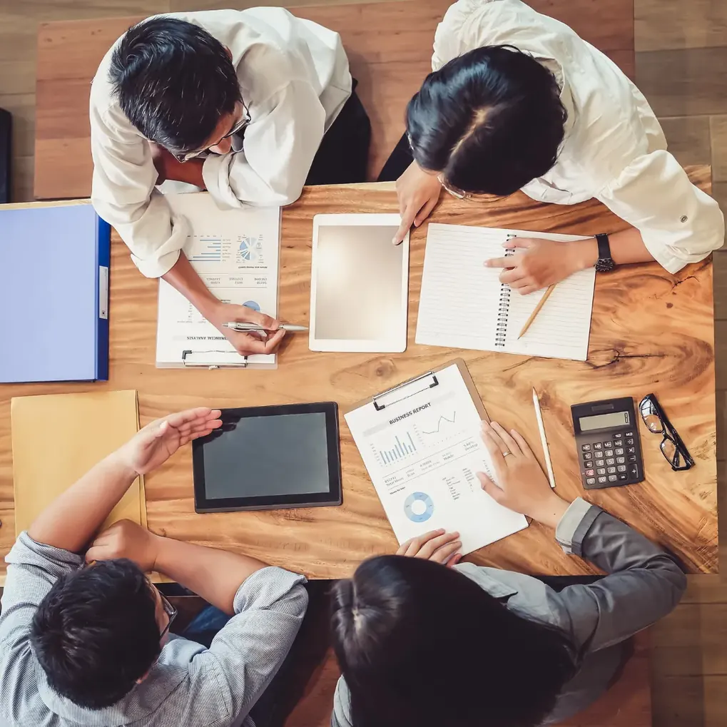 Mesa de trabalho vista do alto, com documentos, tablet e calculadora
